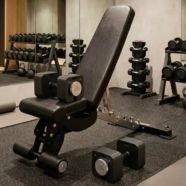 Verstellbare Trainingsbank mit verstellbaren Kurzhanteln und Spiegelwand in Fitnessraum.